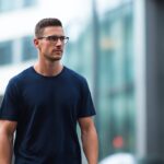 ネイビーのTシャツを着た30代男性。肩のラインが自然に収まり、街中で清潔感のあるバランスよいスタイルに見える。