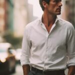 痩せ型の40代男性が、白シャツとスラックスをシンプルに着こなし、ニューヨークの街中を歩いている様子